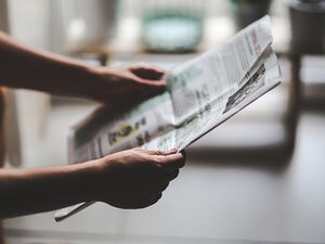 Eine Person hält eine Zeitung in den Händen, denn öffentliche Anzeigen können zu Einbrüchen führen