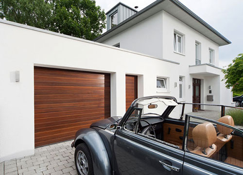 Garagentor in Holzoptik in einem weißen Haus mit modernem Baustil mit einem davor parkenden Käfer Cabrio
